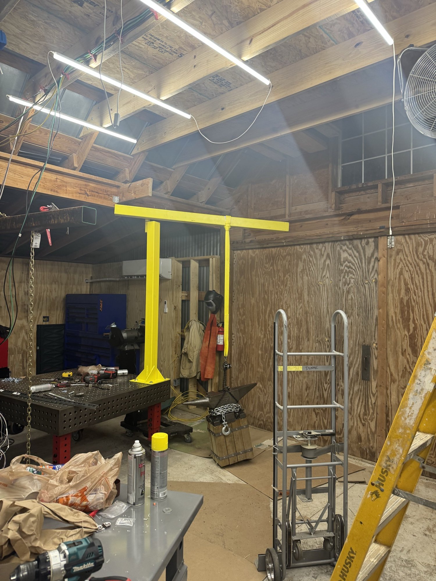 Yellow jib crane bolted to the welding table in the shop