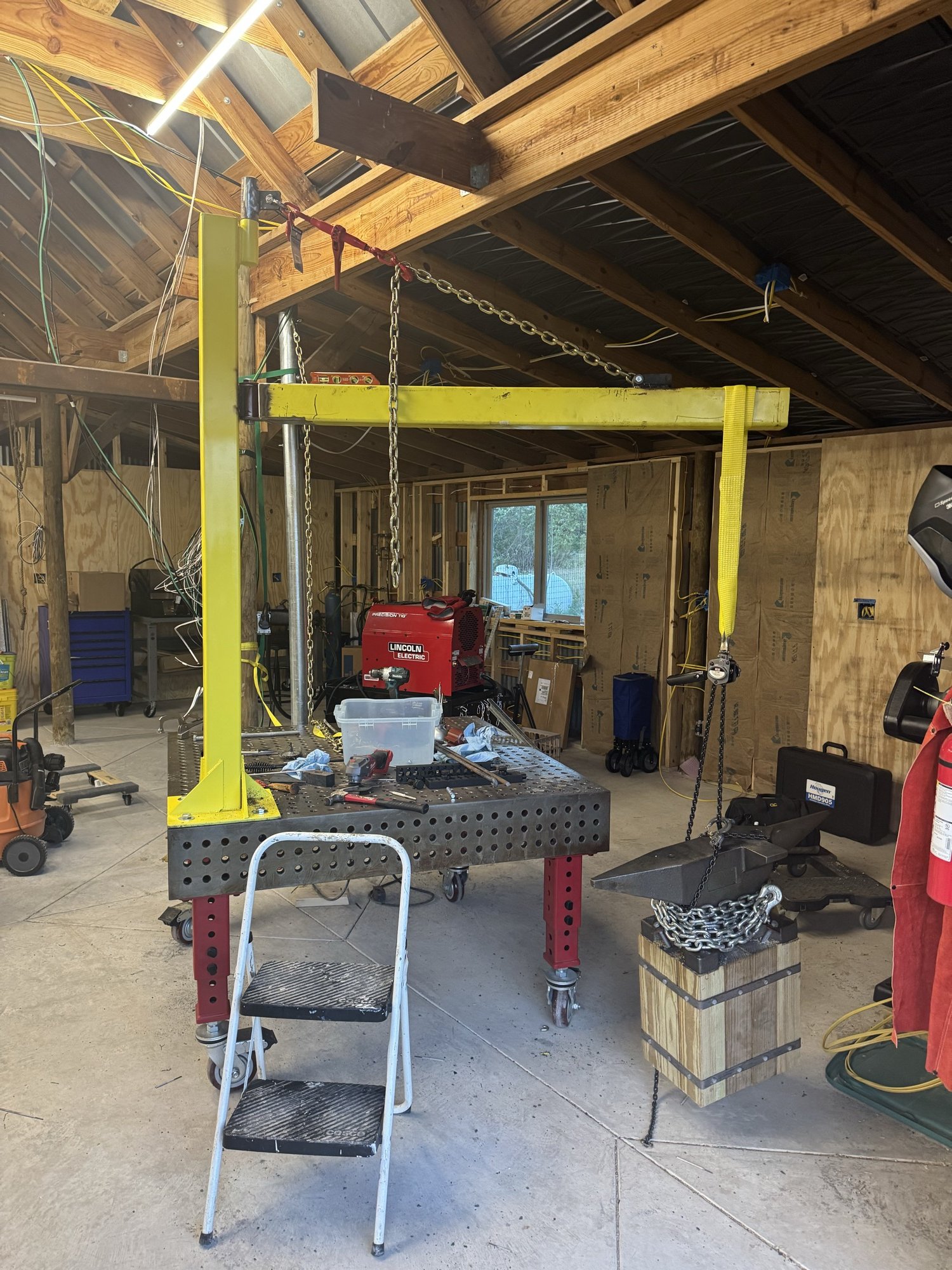 Crane with a second yellow beam hung from the rafters by chain
