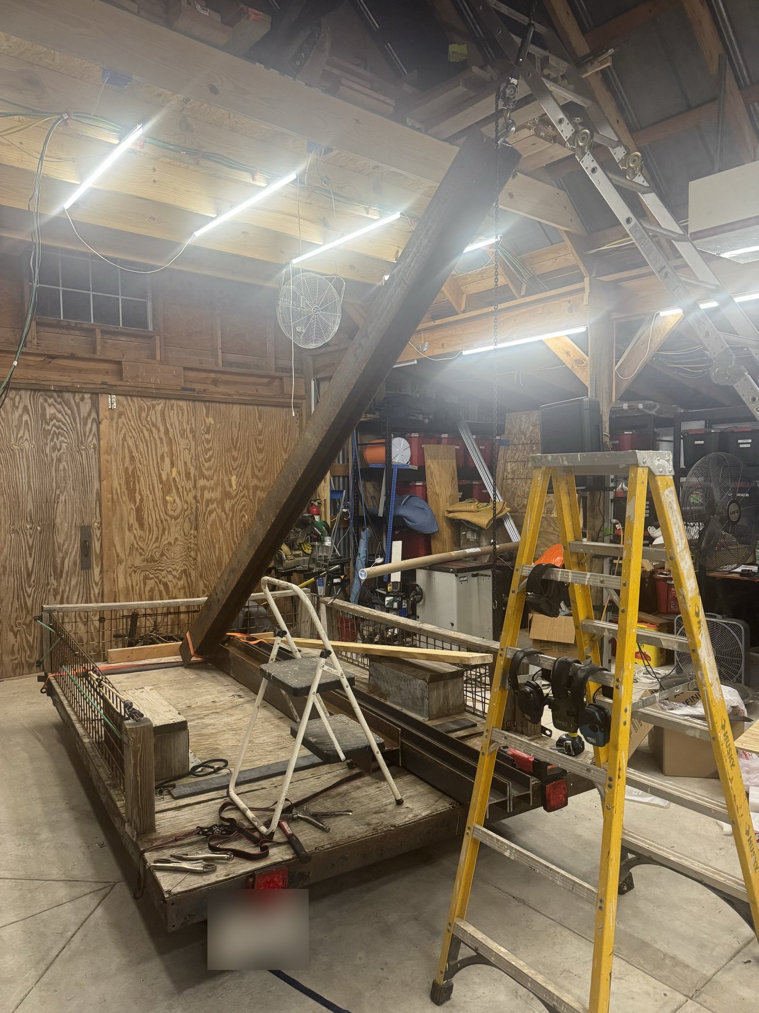Steel beam being lifted off a trailer with a chain hoist