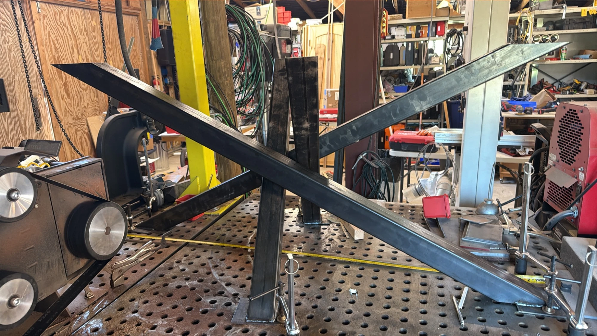 Steel tube legs clamped in an X shape on a welding table